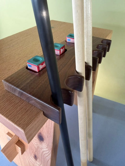 A walnut pool cue holder that allows up to 7 cues to rest along with three different pockets to hold chalk.  